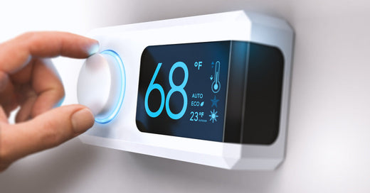 A person's hand twisting a knob on a thermostat. They adjust the temperature to sixty-eight degrees Fahrenheit.