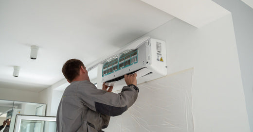 A person in a uniform inspects and installs a piece of heating and cooling equipment inside of a dwelling.