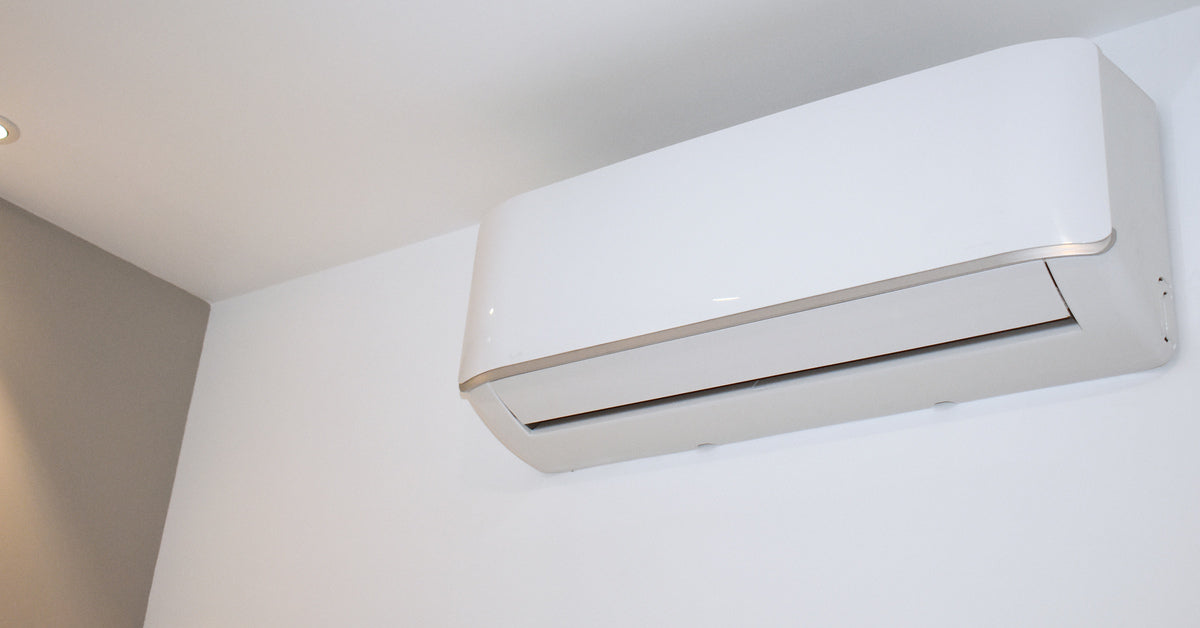 A white mini-split air conditioning and heating system mounted near the ceiling on a plain white wall.