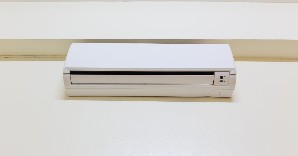 The indoor unit of a mini split system, white in color, mounted to the surface of plain white walls.