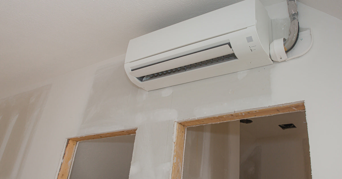 A ductless white mini split installed onto the unfinished wall of a room still undergoing construction.