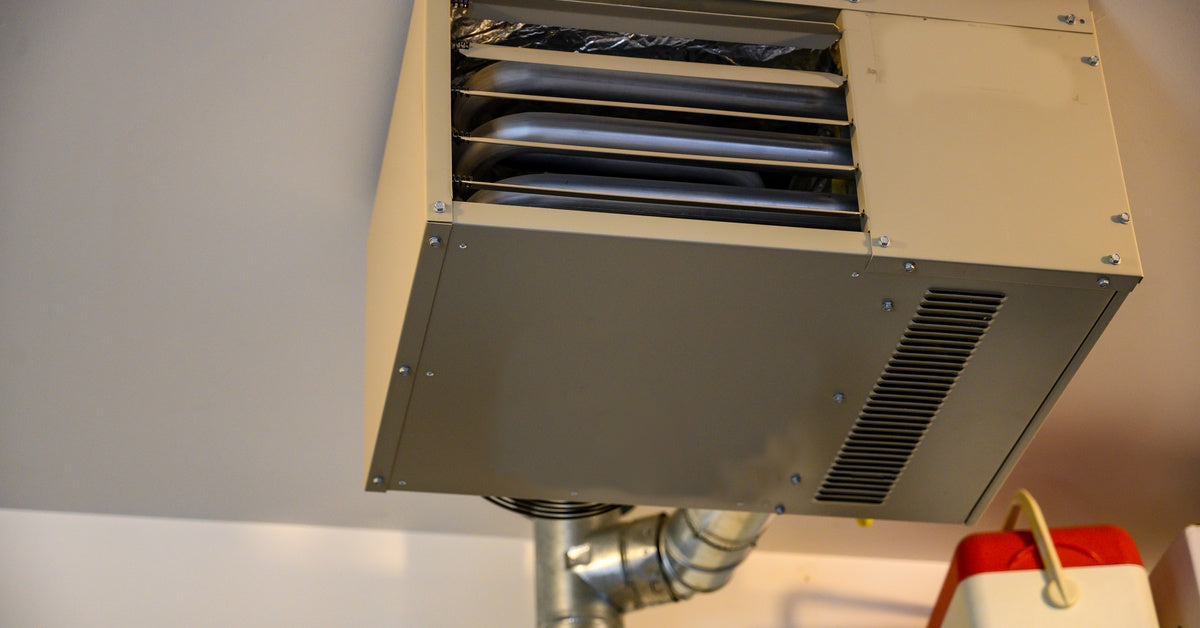A large, older model of an HVAC system mounted to the ceiling of a room. The ceiling and walls are white.