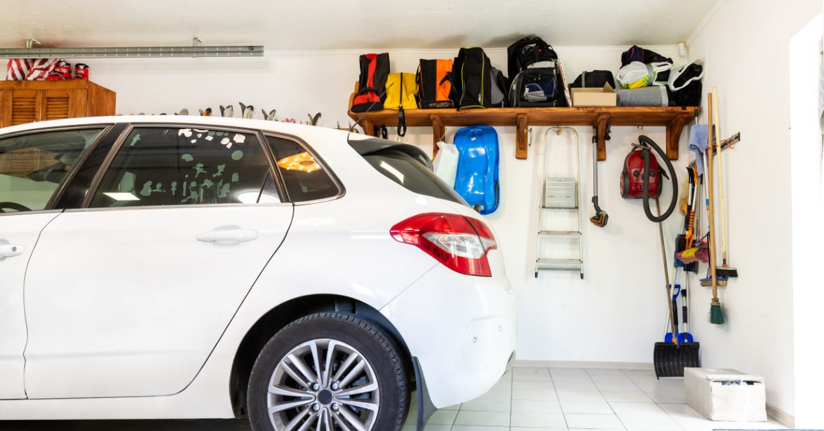 A clean, organized garage interior with a white car, wall shelving, and storage tools, ideal for a ductless mini split system.