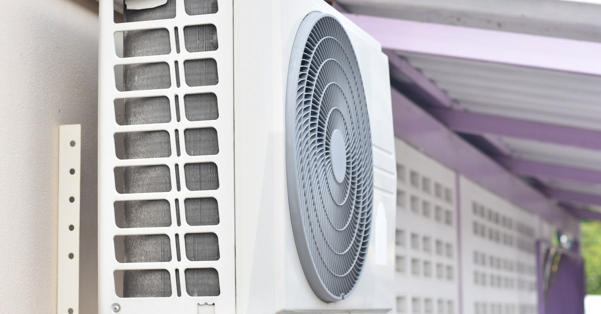 A ductless mini-split outdoor unit with visible fan blades, mounted on a metal bracket outside a home.