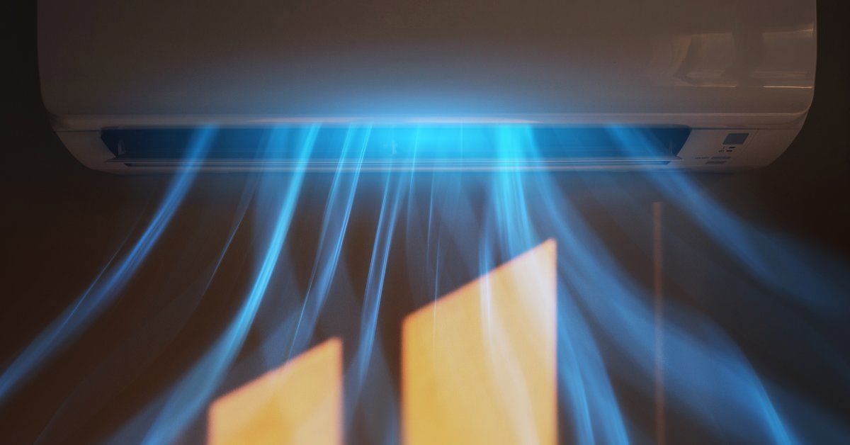 A wall-mounted mini-split air conditioner blows visible cool blue airflow across a sunlit room, showing indoor airflow.